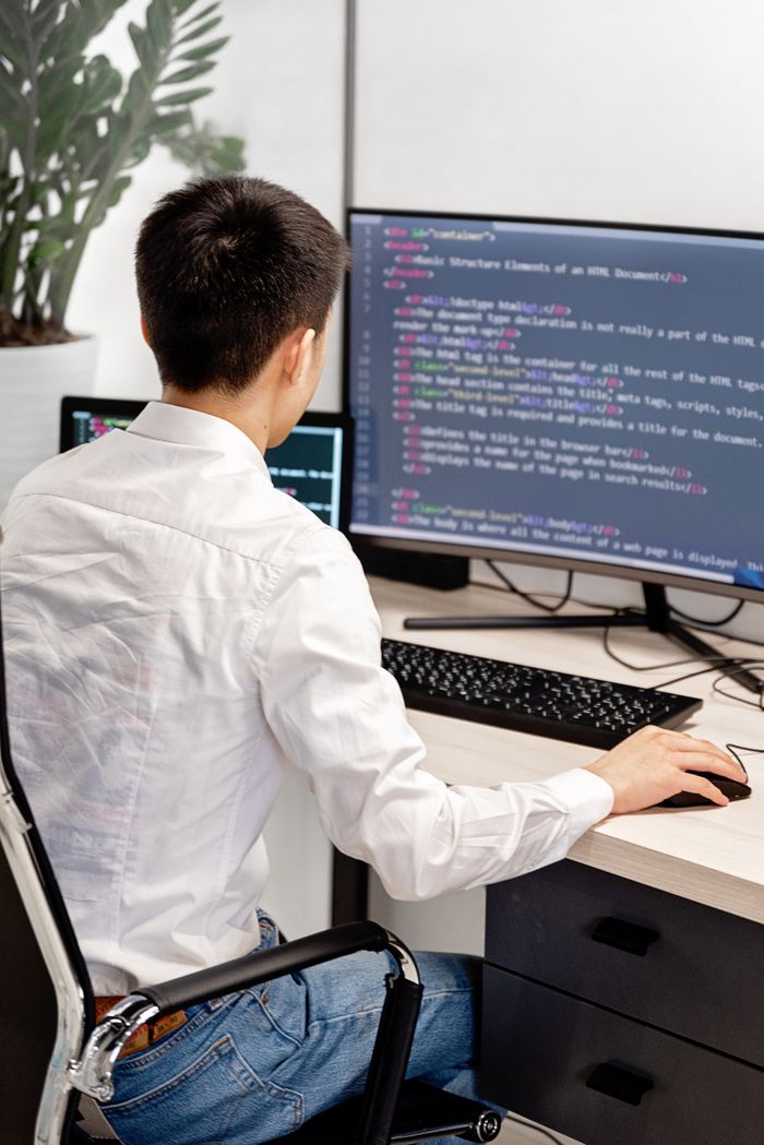 The Art of Drawing Readers In: Your attractive post title goes here Back view of a programmer in a white shirt coding in an office workspace.